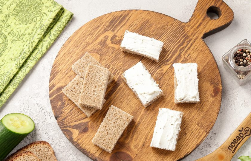 1. Этап. Канапе со шпротами и огурцом: Намажьте хлеб творожным сыром. У меня творожный сыр с зеленью.