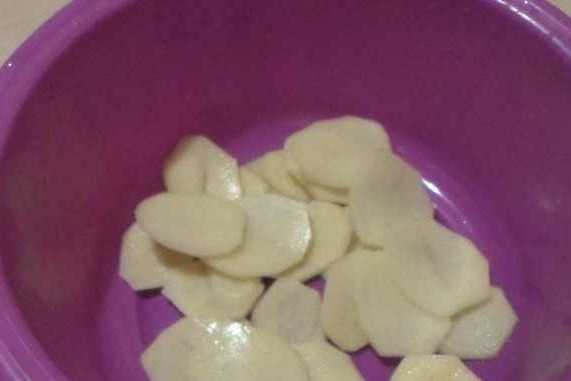 1. Этап. Скумбрия, тушенная в сметане: Картофель почистите, помойте и нарежьте тонкими пластинками. Уложите его в холодную воду на 10 минут, чтобы ушёл крахмал.