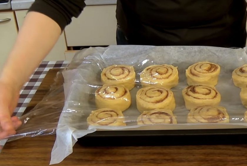 1. Этап. Булочки с тыквой и корицей: 5. Разрежьте рулет при помощи нити на 12 одинаковых частей. Выложите в форму, застеленную бумагой для выпечки, накройте пищевой пленкой и оставьте в теплом месте на 40 минут.