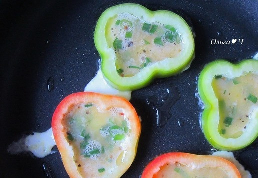 1. Этап. Бутерброд с колбасками и омлетом: Разогрейте растительное масло в сковороде, выложите кружочки перцев. Аккуратно залейте в перцы по 1 ст. л. яичной массы, затем поровну разлейте оставшуюся массу. Накройте крышкой, готовьте на огне ниже среднего 2-3 минуты.