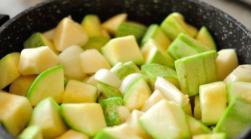 1. Этап. Холодный суп-пюре из кабачков: В сотейник с толстым дном или казанок влейте растительное масло и разогрейте его на плите. Кабачки вымойте и порежьте на крупные куски. Картофель, лук и чеснок почистите, промойте под водой и также нарежьте кубиками. Выложите овощи в сотейник и слегка обжарьте.