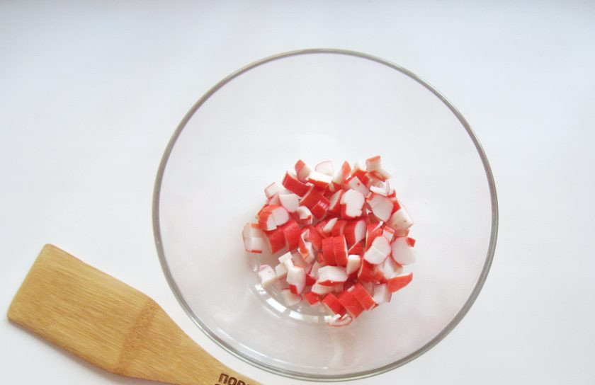 1. Этап. Салат Фантазия с крабовыми палочками: Крабовые палочки нарежьте кубиками и выложите в салатник.