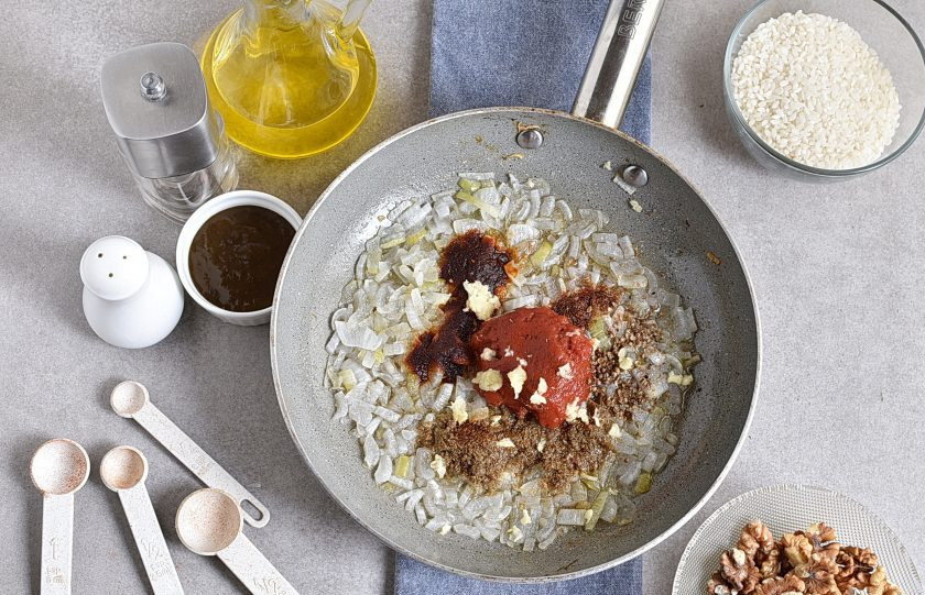 1. Этап. Харчо из говядины с ткемали: Добавьте томатную пасту и пряности, кориандр крупно потолките, выдавите чеснок. Перемешайте и немного прогрейте пару минут до появления аромата.