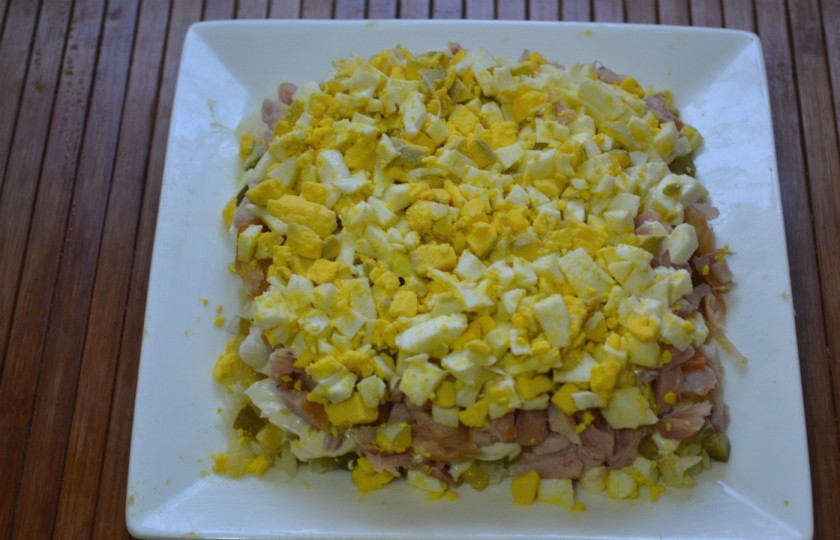 1. Этап. Салат новогодний Адвент: Мелко нарежьте или натрите на крупной терке яйца, распределите их по поверхности салата. Сверху обильно смажьте майонезом со всех сторон.