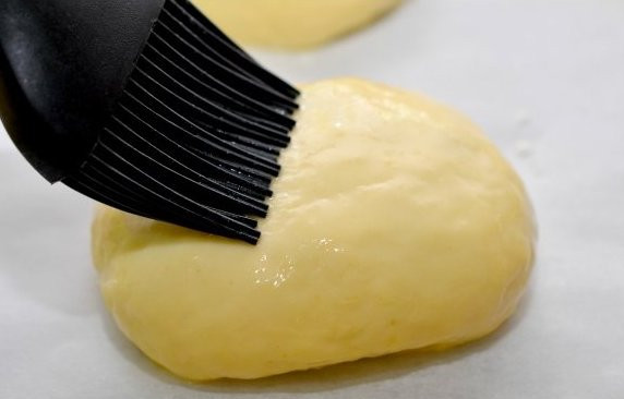 1. Этап. Сдобные пирожки с творогом: Затем мы посыпаем стол мукой, берем один шарик и разминаем его руками в лепешку. В середину лепешки кладем начинку, соединяем края теста и формируем небольшой пирожок, то же самое делаем с остальным тестом. Выстилаем противень пекарской бумагой, выкладываем на нее пирожки швом вниз и оставляем еще на 20 минут постоять. Тем временем взбиваем яйцо со сливками и смазываем этой смесью подошедшие пирожки.