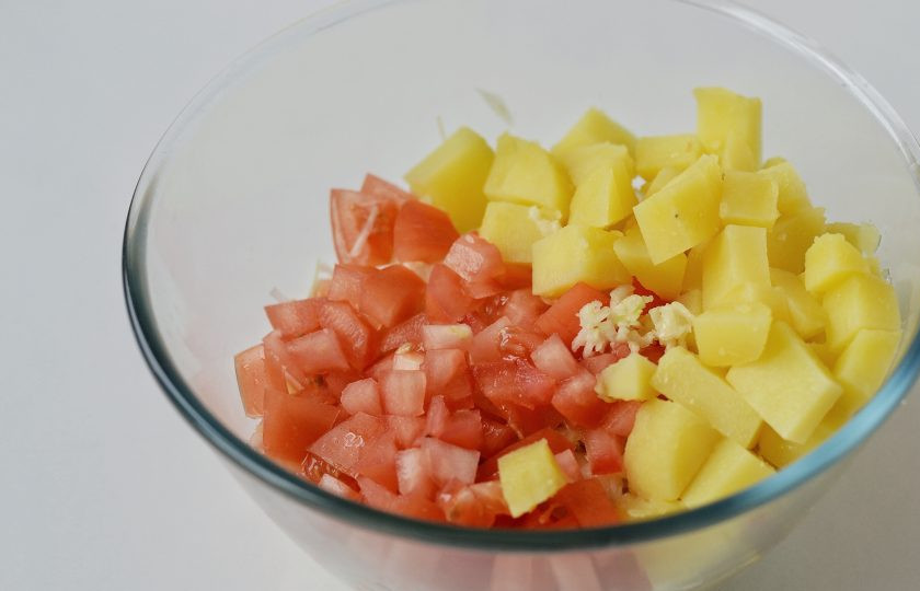 1. Этап. Салат с капустой и нутом: Помидор и картофель нарежьте кубиками, чеснок пропустите через пресс.
