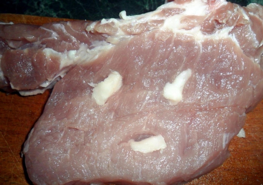 1. Этап. Нежные стейки из свинины с чесноком в духовке: 1. Стейки зачищаю от пленки, хорошенько мою и вытираю насухо бумажным полотенцем. Чеснок чищу и нарезаю небольшими кусочками, в мясе делаю надрезы, куда вставляю кусочки чеснока.