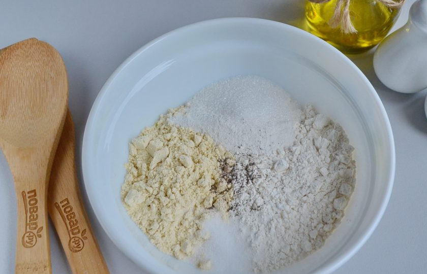 1. Этап. Мини корн-доги: В глубокой посудине соедините кукурузную муку с пшеничной, сахаром, солью, разрыхлителем и перцем. Перемешайте.