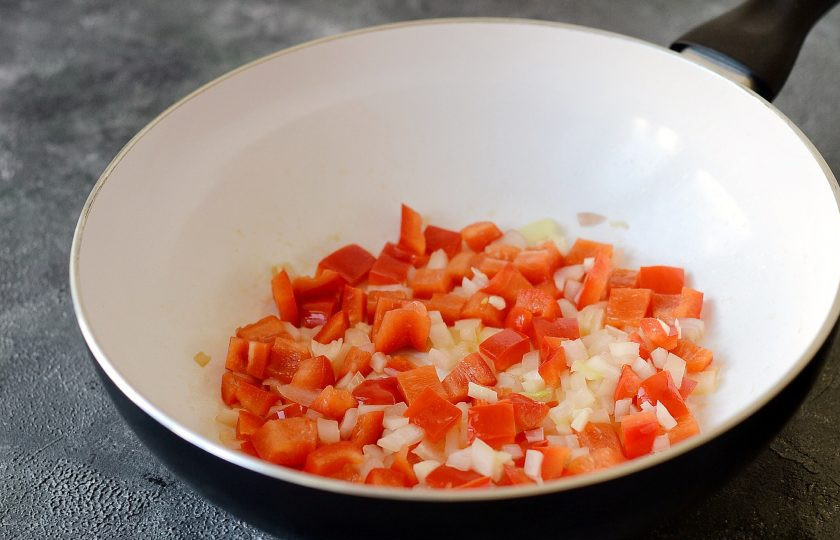 1. Этап. Пилав из булгура с нутом: Болгарский перец и репчатый лук нарежьте кубиками, чеснок мелко порубите. Разогрейте масло в сковороде с толстым дном и обжарьте овощи 7-8 минут. Добавьте специи и жарьте еще 1 минуту.