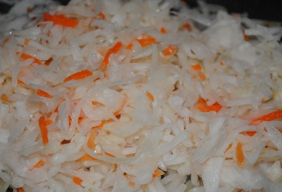 1. Этап. Свиная рулька по-немецки: Капусту отожмите от рассола. Добавьте её в сковороду и тушите вместе с луком 10 минут.