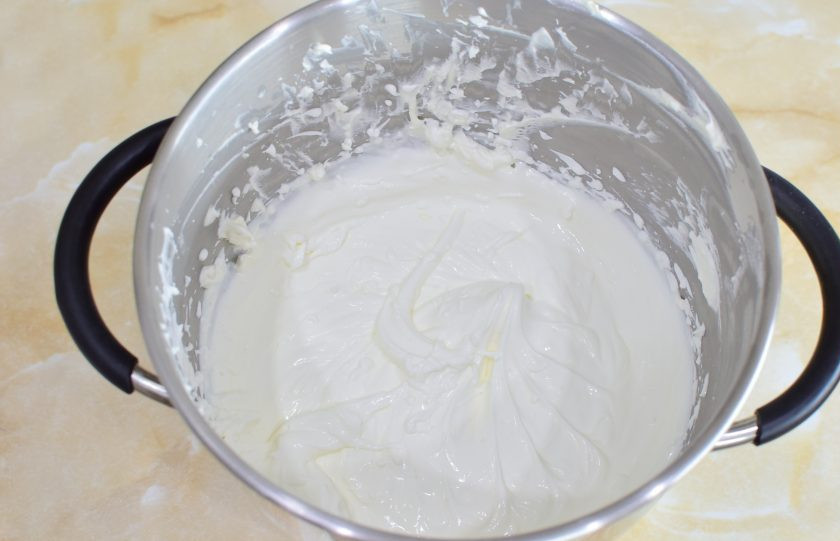 1. Этап. Медовик с малиной: Для приготовления крема взбейте сметану с сахарной пудрой. Оставьте 200 грамм сметаны и немного пудры для внешнего оформления торта.