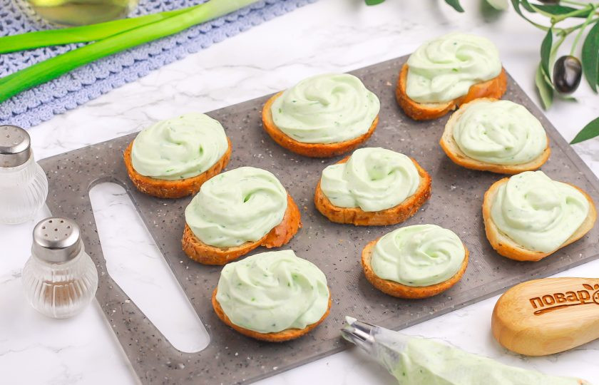 1. Этап. Канапе Яйца змеи: Выложите творожный крем в кулинарный пакет и отсадите на ломтики багета.