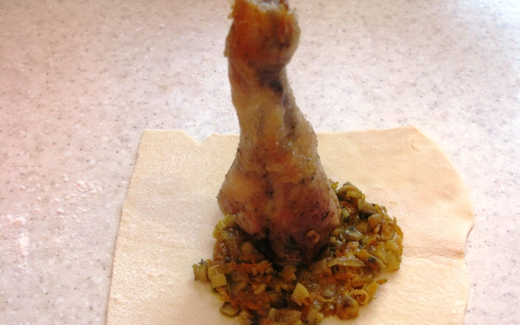 1. Этап. Ножка куриная в мешочке: Тесто раскатайте и нарежьте квадратами. На каждый квадрат поместите немного обжаренных овощей, одну ножку и соберите тесто вокруг ножки в виде мешочка. Чтобы не распалось, завяжите стеблем зеленого лука.