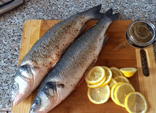 1. Этап. Сибас запеченный: 1. Духовку включите, пусть разогревается до 190 градусов. Противень смажьте маслом. Рыбку вымойте, очистите. Нарежьте тонкими кольцами лимон и луковицу.