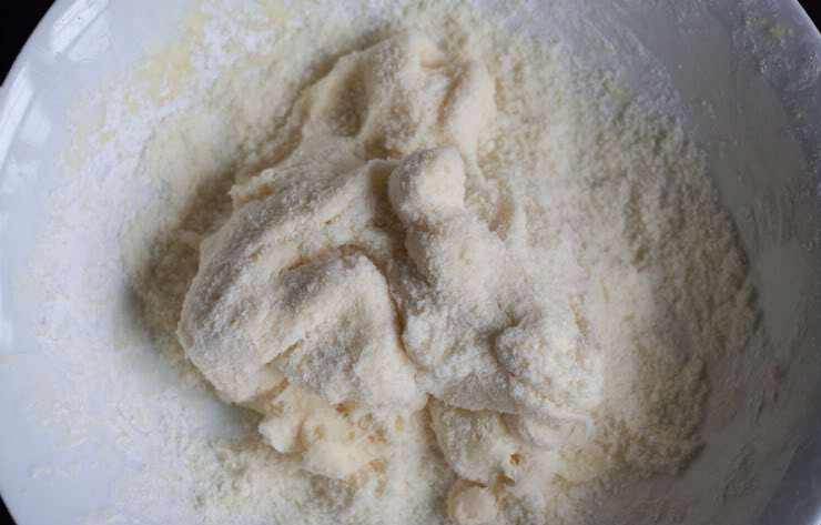 1. Этап. Бездрожжевое тесто на булочки: Пока тесто остывает, разогрейте духовку до 200 градусов. Затем венчиком взбейте яйцо и отправьте в остывшее тесто, вымешайте руками. Затем натрите сыр и добавьте в тесто. Еще раз вымешайте.