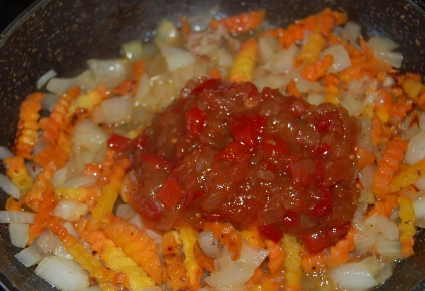 1. Этап. Тушеная картошка с тушенкой: Когда лук стал прозрачным, добавьте в поджарку томатную пасту. Размешайте овощи вместе с томатной пастой. Потушите 1-2 минуты.