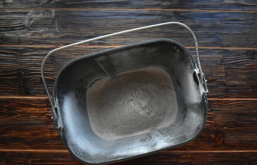 1. Этап. Цельнозерновой хлеб на закваске в хлебопечке: Извлеките из устройства емкость. Установите на дно ведерка лопатку для замешивания теста. Добавьте соль. Всыпьте просеянную цельнозерновую муку.