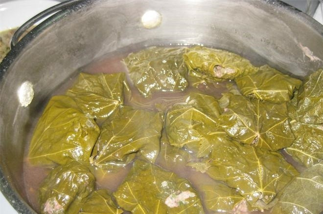 1. Этап. Армянские голубцы: 2. Виноградные листья заливаем кипятком и оставляем на 7 минут, после этого откидываем их на сито. В каждом листе удаляем толстую часть, и затем выкладываем фарш и заворачиваем, складываем все в кастрюлю. Для варки голубцов заливаем их водой или бульоном, кладем оставшиеся виноградные листья и ставим на огонь, солим немного. Варим после закипания на минимальном огне полтора-два часа.