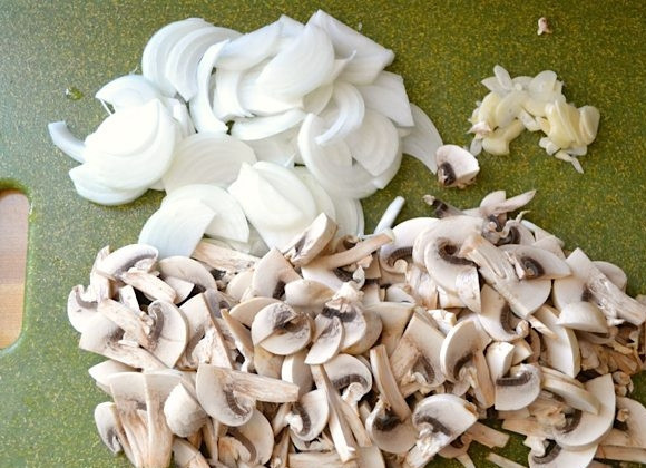 1. Этап. Макароны с сосисками и грибами в томатном соусе: 4. Тем временем очистите лук, чеснок и грибы. Нарежьте лук полукольцами, тонкими ломтиками грибы и измельчите чеснок.