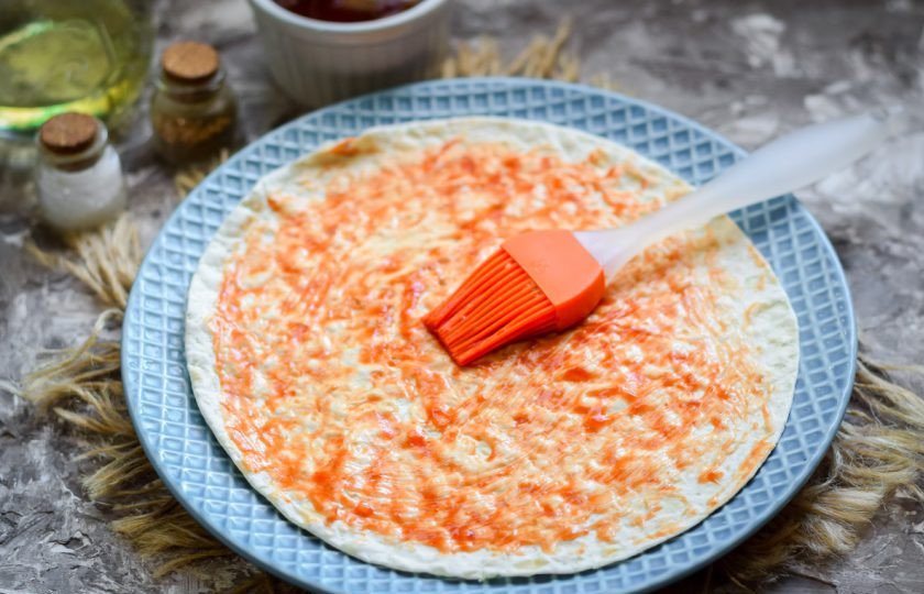 1. Этап. Пицца на сковороде за 15 минут: Подготовьте три листа лаваша, для удобства используйте круглый лаваш, который подходит под диаметр вашей сковороды. Смажьте первый лаваш соусом.