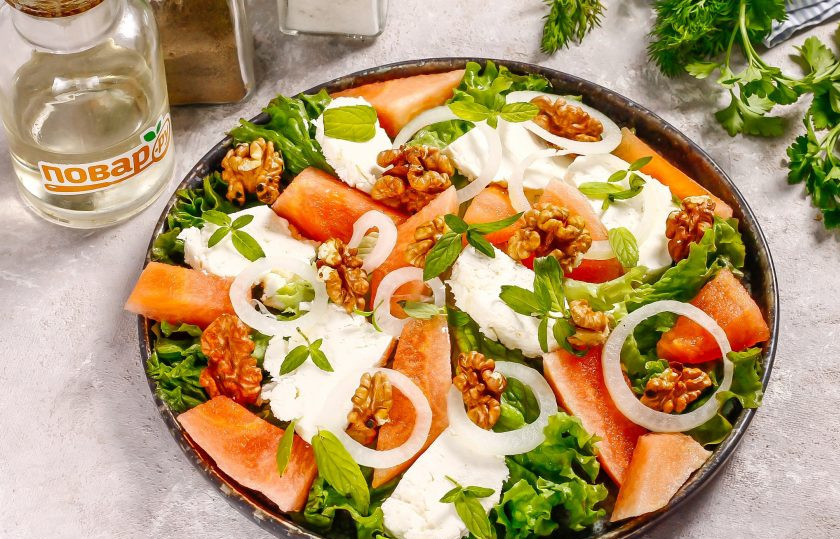 1. Этап. Салат с арбузом от Джейми Оливера: Репчатый лук очистите от кожуры, промойте и половину нарежьте тонкими кольцами. Выложите на салат. Добавьте промытые листочки мяты и ядра грецких орехов. Если есть свободное время, то орехи сначала можно слегка подсушить на сковороде.