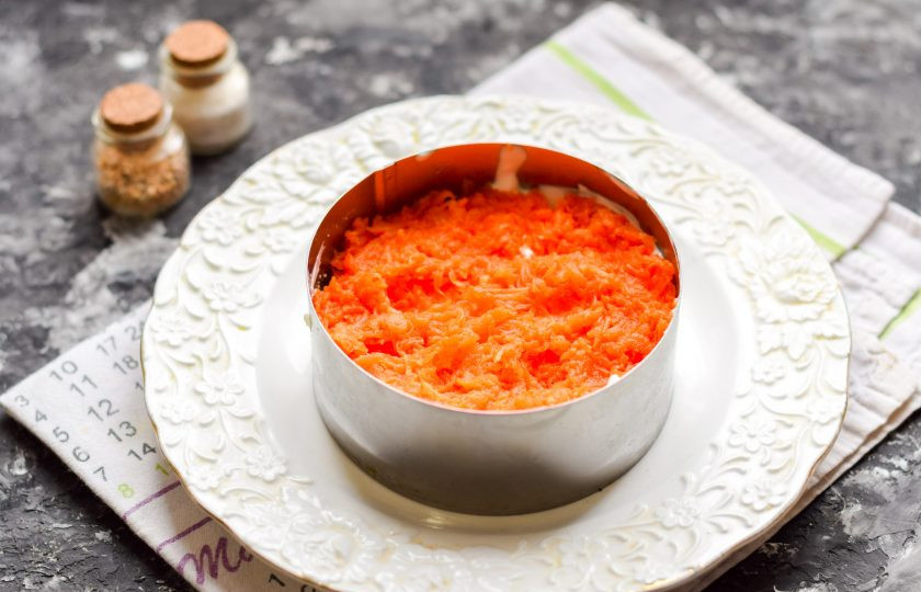 1. Этап. Салат Мимоза с красной рыбой: Поверх картофеля выложите натертую мелкой стружкой морковь.