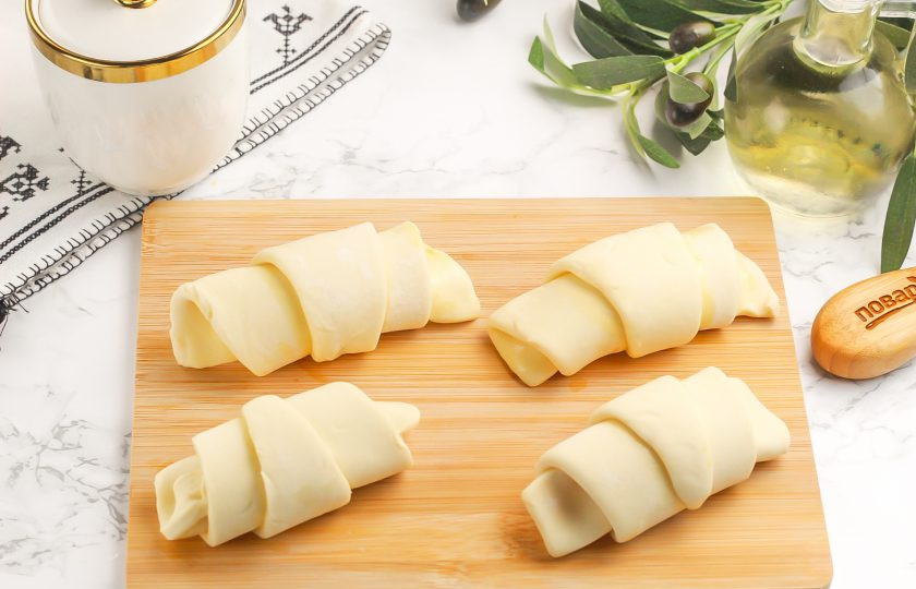 1. Этап. Круассаны в аэрогриле: Начиная от широкого края с начинкой, заверните треугольники рулетиком, слегка сплющивая края и стараясь поместить узкий конец теста в середину. Обязательно кончик теста оставляйте под самим круассаном, чтобы он не развернулся при выпекании.