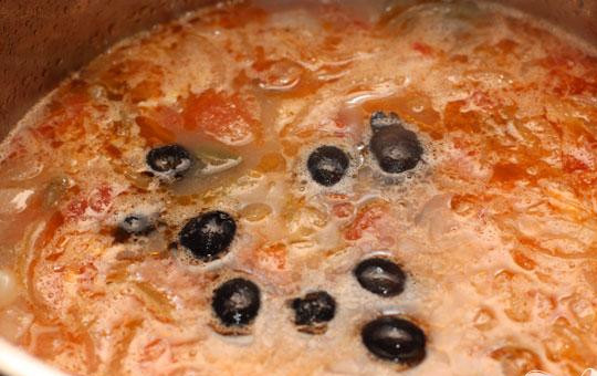 1. Этап. Рыбная солянка с семгой: 6. Пассированные овощи кладем в суп, доводим до кипения и минут пятнадцать готовим еще. Теперь добавляем рыбу и варим еще пять минут. Солим по вкусу. Маслины добавляем в самом конце. Огонь выключаем. Когда будем подавать, добавляем в тарелку нарезанную зелень и ломтик лимона.