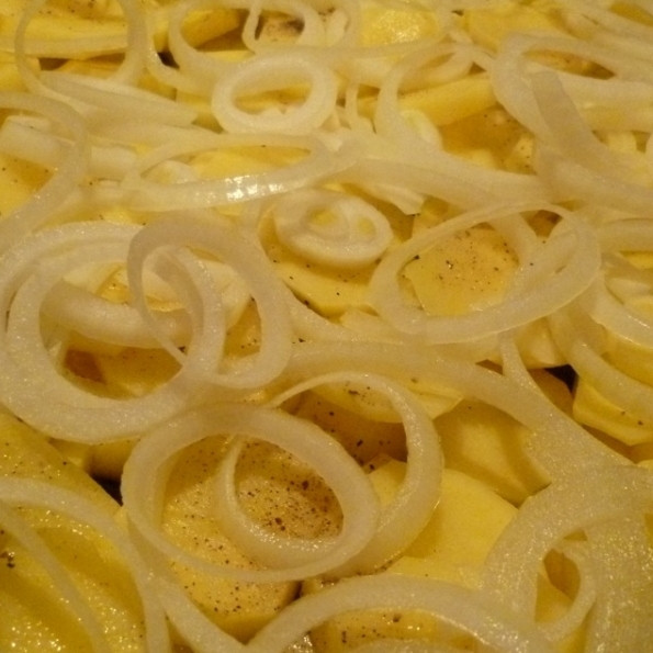 1. Этап. Мясо по-французски с картофелем: Лук чистим, нарезаем тонкими кольцами и равномерно укладываем поверх картофеля. Солим, перчим.