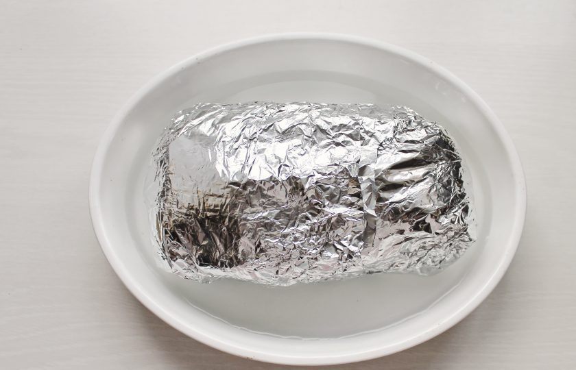 1. Этап. Буженина с яблоками: Выложите мясо на яблоки и плотно заверните в фольгу. В форму для запекания налейте 200 миллилитров воды и выложите свинину в фольге.