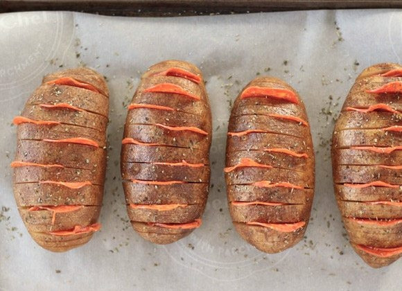 1. Этап. Картошка-гармошка с пепперони: 2. Выложите картофель на противень, застеленный пергаментом. В некоторые разрезы вставьте ломтики пепперони, посолите и поперчите, добавьте специи, полейте растительным маслом.