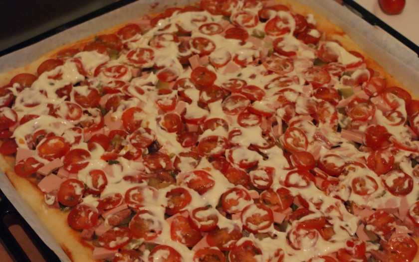 1. Этап. Пицца из дрожжевого теста: 4. Моем и нарезаем колечками помидоры. На тесто с кетчупом выкладываем ранее обжаренный лук с зеленью, затем колбасы с огурцом и сверху — помидорки, поливаем майонезом по вкусу и размазываем его.
