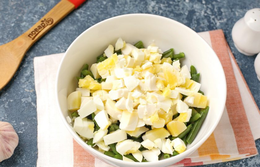 1. Этап. Салат из зеленой фасоли с яйцами: Добавьте нарезанные кубиками яйца.