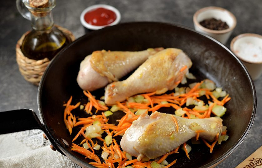 1. Этап. Куриные голени тушеные в томатном соусе с грибами: Добавьте в сковороду измельченный лук и морковь, обжарьте вместе с ножками несколько минут до мягкости.