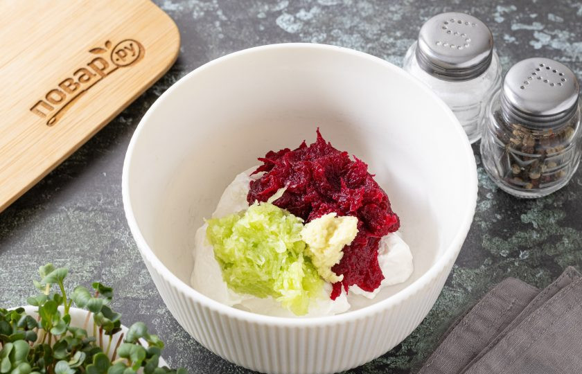 1. Этап. Свекольный дзадзики: Огурец очистите от кожуры и натрите на мелкой терке, затем отожмите от сока. Свеклу тоже очистите, натрите на мелкой терке и отожмите. Чеснок пропустите через пресс. Добавьте подготовленные ингредиенты в миску и все перемешайте.