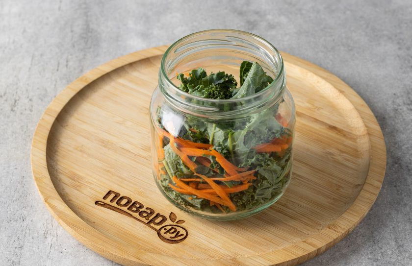 1. Этап. Капуста кале на зиму: В чистую стерилизованную банку выложите слоями листья кале и морковь. Укладывать нужно плотно, утрамбовывая листья.