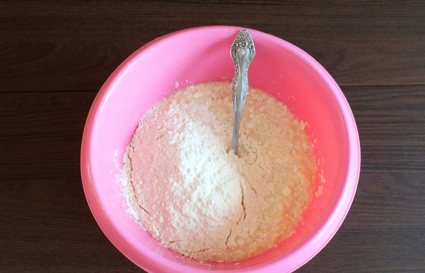 1. Этап. Творожные пончики с яблоком: Всыпьте большую часть муки.