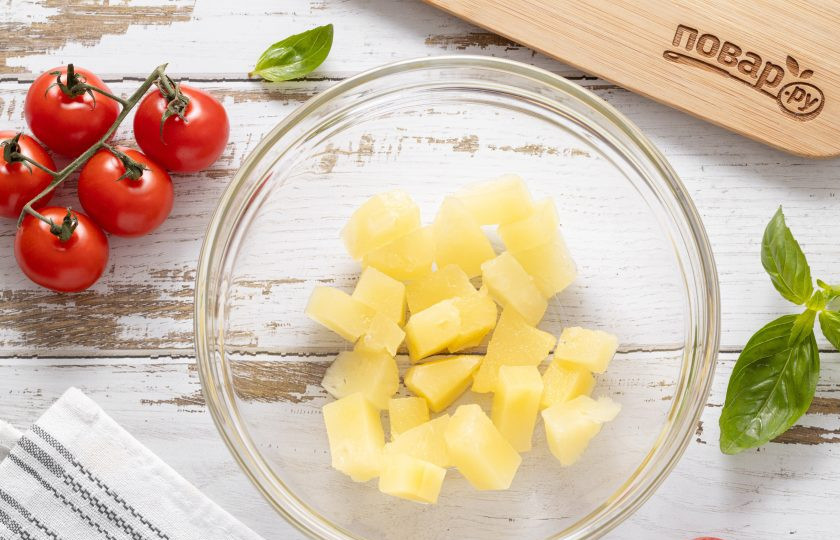 1. Этап. Салат с ананасом, помидорами и сыром: Слейте сироп от консервированных ананасов. Ломтики ананаса порежьте на кубики среднего размера. Переложите в глубокую миску.