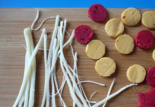 1. Этап. Елка из овощей и тунца: Из ломтика плавленого сыра с помощью вырубки для печенья вырежьте кружки для украшения, развяжите сырные нити (косичку), из красного твердого сыра вырубкой вырежьте звездочку на макушку елки, а также кружки и отложите их в сторону.