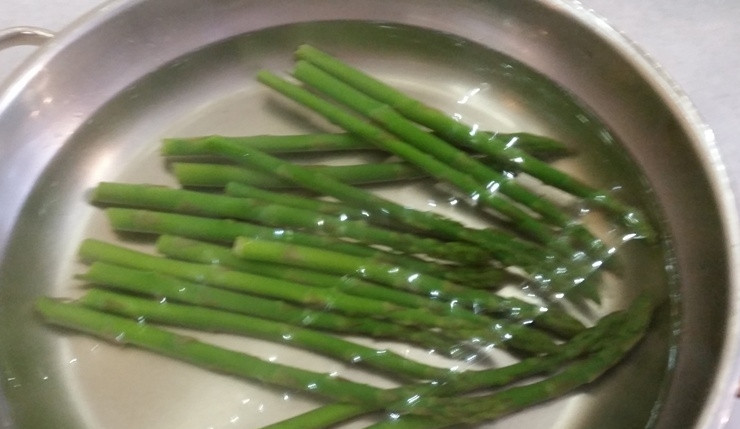 1. Этап. Салат из спаржи: В большой сковороде вскипятите воду. Положите в неё промытую спаржу. Варите её на небольшом огне в течение 3-х минут под крышкой. Затем слейте эту воду, а спаржу переложите в ледяную. После высушите её.