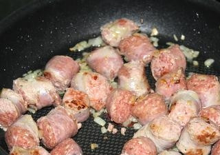 1. Этап. Подливка из колбасы: Выложить колбасу и обжаривать 5 минут, помешивая. Затем добавить лук, перемешать.