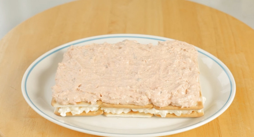 1. Этап. Лучший закусочный торт из крекеров и рыбной консервы: 7. Равномерно распределите рыбный слой начинки на втором слое крекеров.