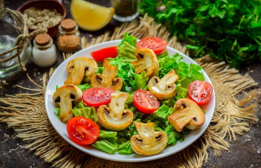 1. Этап. Зеленый салат с грибами: Черри ополосните и просушите. Нарежьте томаты половинками, разложите поверх салата, между грибов.