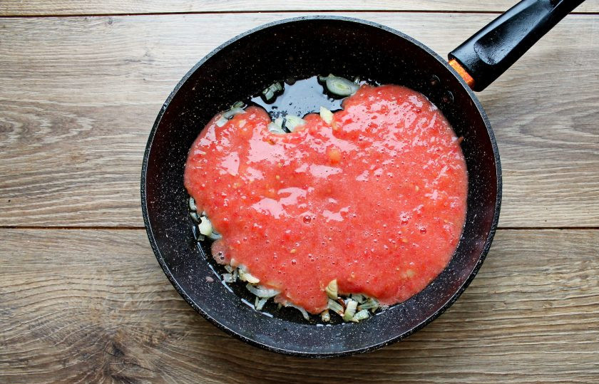 1. Этап. Сосиски на сковороде тушеные в томатном соусе: Помидоры сполосните, порежьте на дольки и измельчите до однородности. Перелейте томатную массу к обжаренным овощам.