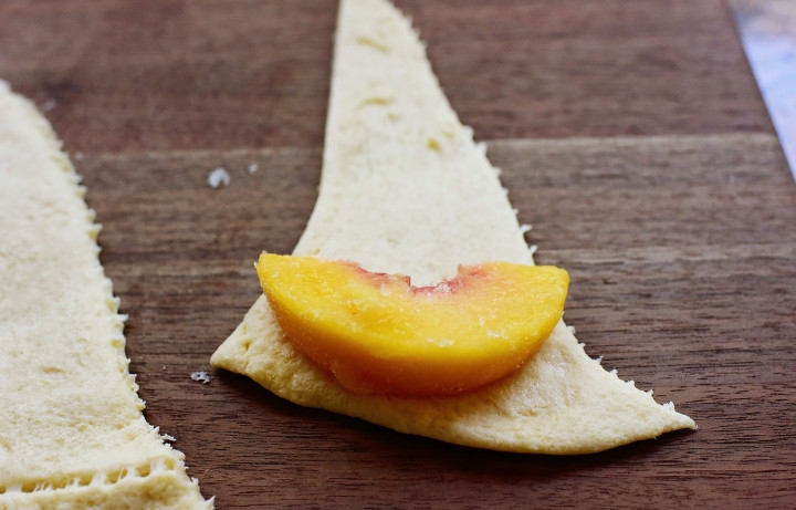 1. Этап. Рогалики с персиком: 1. Разрежьте слоеное тесто на треугольники, чтобы завернуть дольку персика в рогалик.