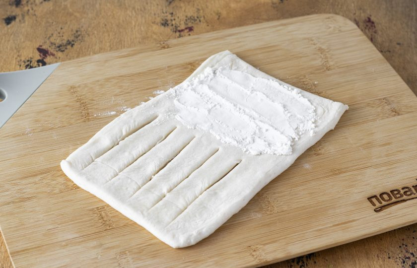 1. Этап. Слойки с консервированными персиками: Сделайте на одной половине треугольника надрезы, но не доходите до конца. Второй край присыпьте крахмалом.