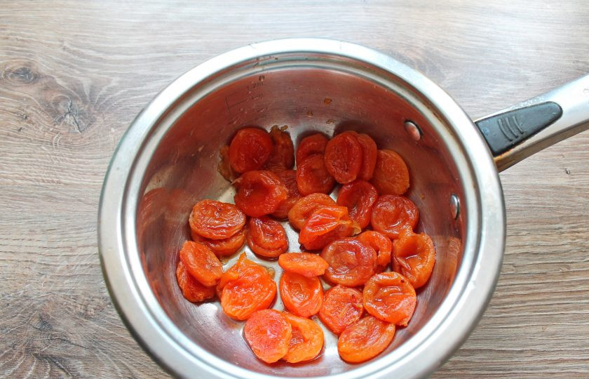 1. Этап. Торт Вриндаван: В чистую кастрюлю выложите промытую курагу, влейте 200 миллилитров воды, всыпьте сахар и поставьте на медленный огонь. Варите в течение 15 минут.