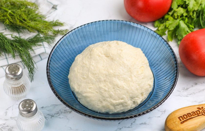 1. Этап. Быстрая пицца: Накройте емкость пищевой пленкой или полотенцем и оставьте на 10-15 минут. В это время нарежьте сосиски кружочками, помидоры ломтиками, а твердый сыр натрите на терке.