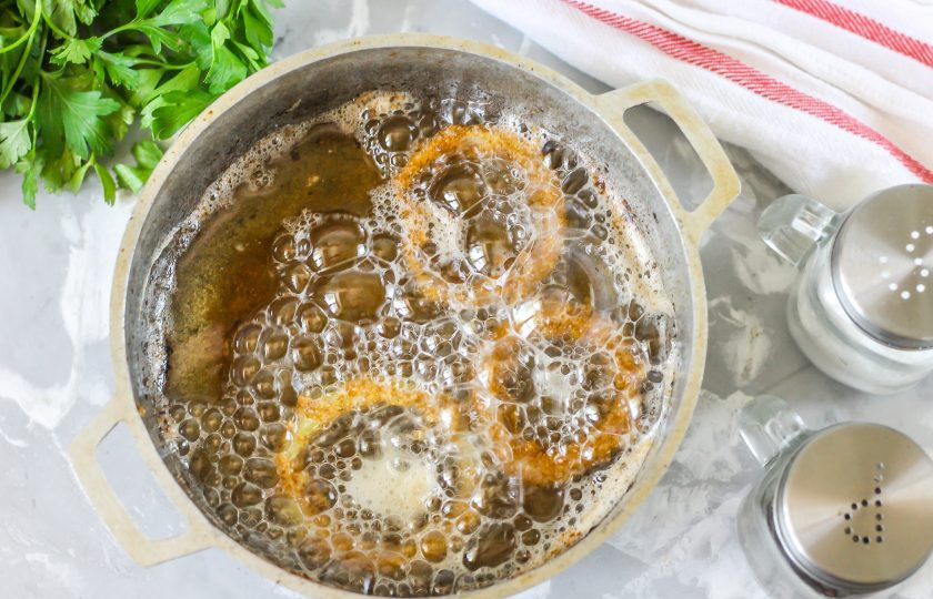 1. Этап. Хрустящий жареный лук: В казане или ковше с антипригарным дном прогрейте растительное масло до кипения и лишь тогда выкладывайте по 2-3 кольца в масло, жаря до готовности примерно 1-2 минуты. В неразогретом масле весь кляр с колец спадет и масло будет дымить!