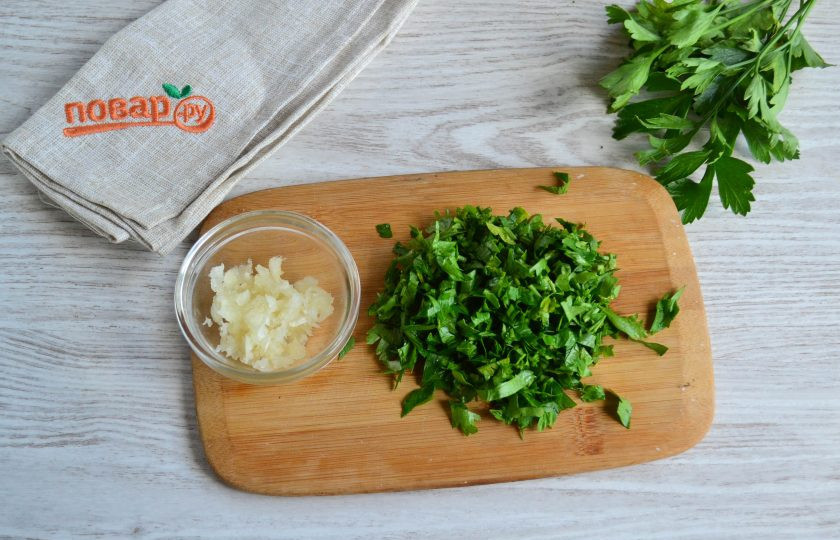 1. Этап. Перец с чесноком и петрушкой на зиму: Зубчики чеснока измельчите с помощью пресса, петрушку промойте и мелко порубите.